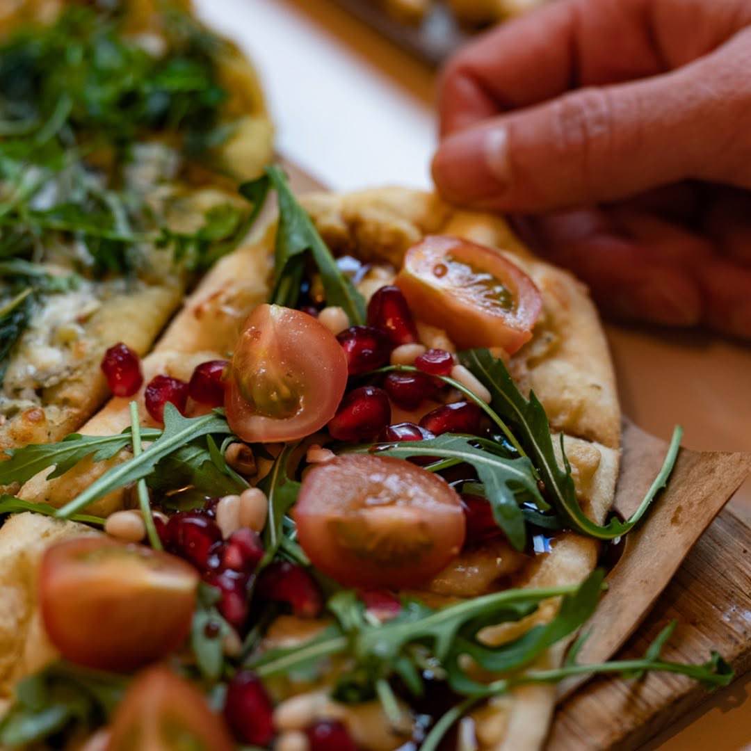 Fresh flatbread topped with rocket, tomato and pomegranate